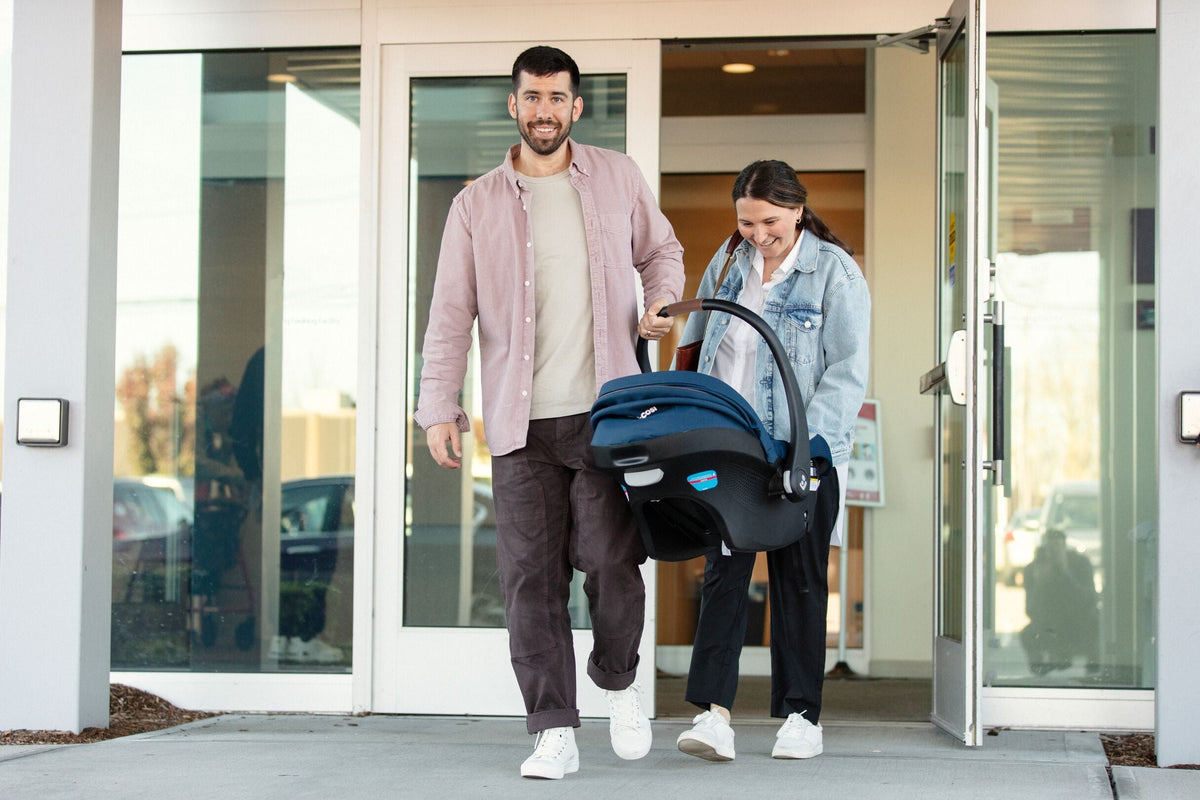 mother and father carrying infant car seat