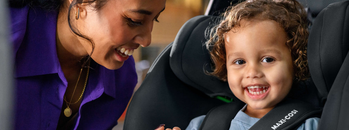 mother smiling at child in car seat