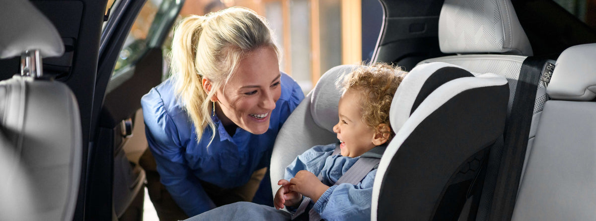 mother smiling at child in car seat