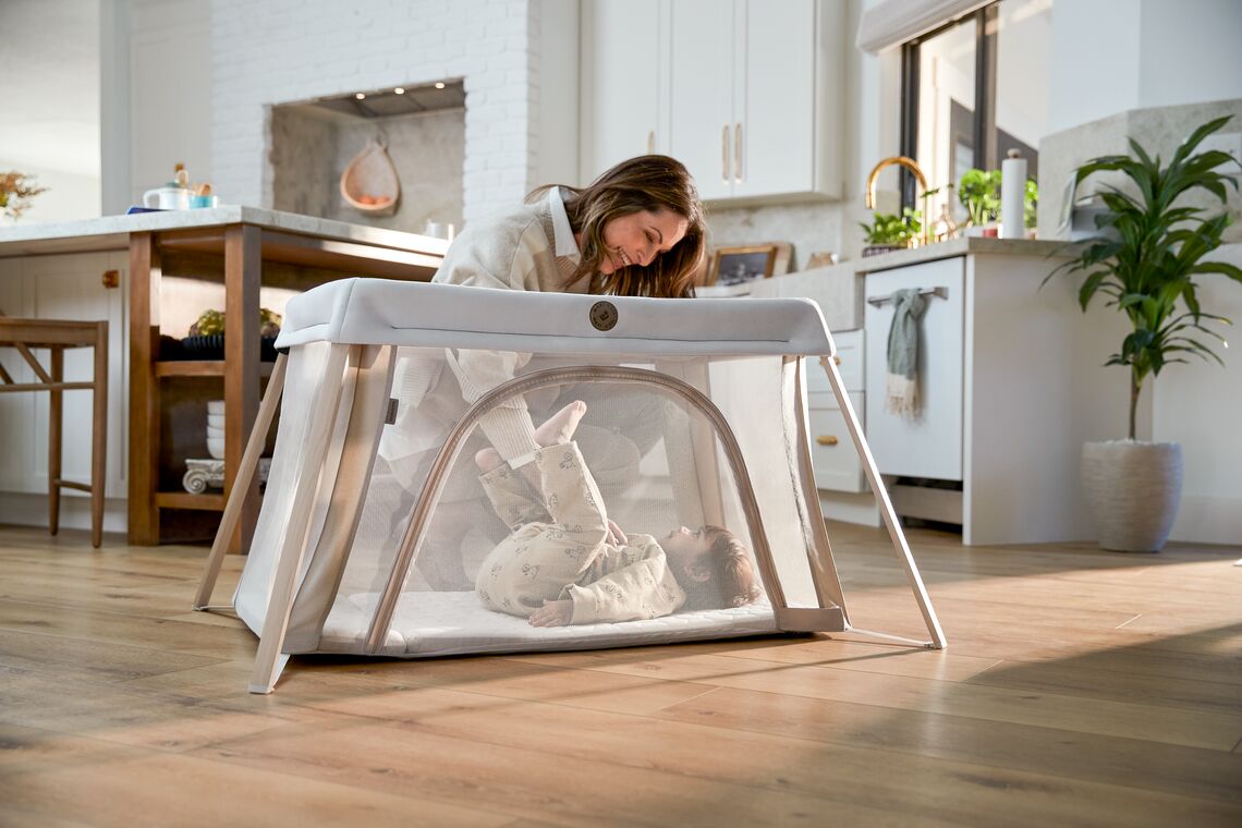 Mom putting baby in play yard