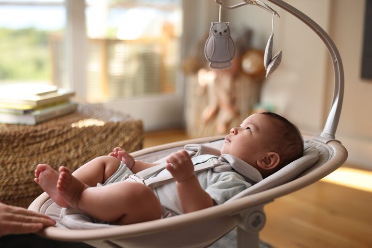 Child in a baby swing looking up at toys