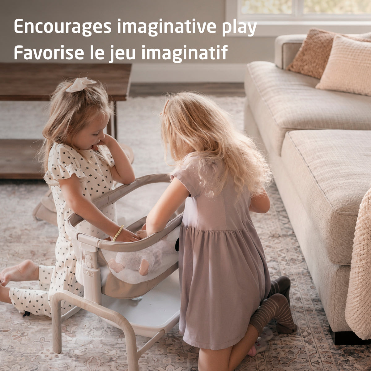 Two young children playing together and tending to a baby doll in the Iora pretend play bassinet.