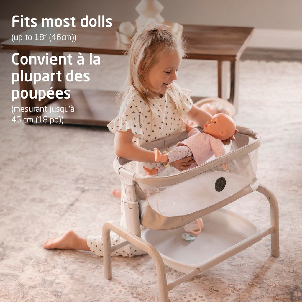 Smiling child holding a baby doll up to 18 inches (46 cm) in the Maxi-Cosi Iora doll bassinet.