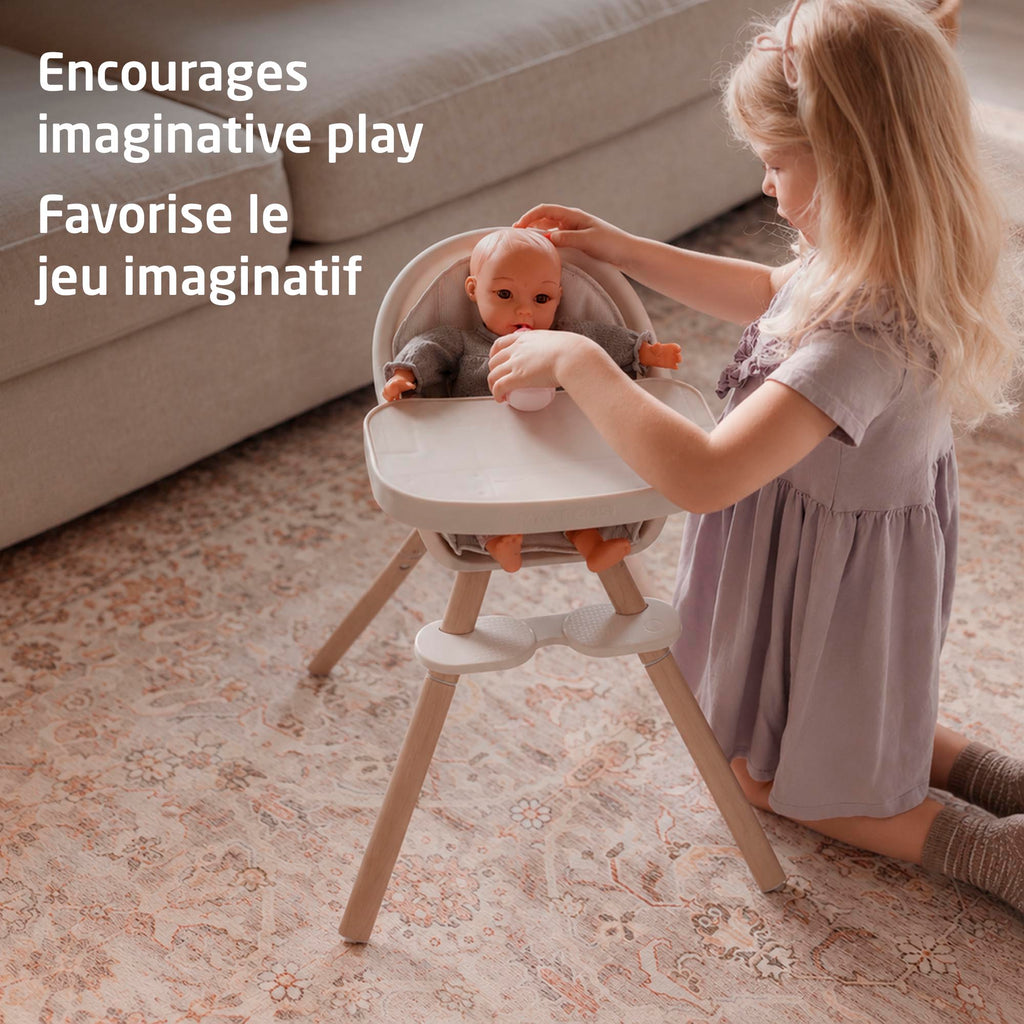 Young child tending lovingly to a doll in the Maxi-Cosi Moa high chair to encourage imaginative pretend play.