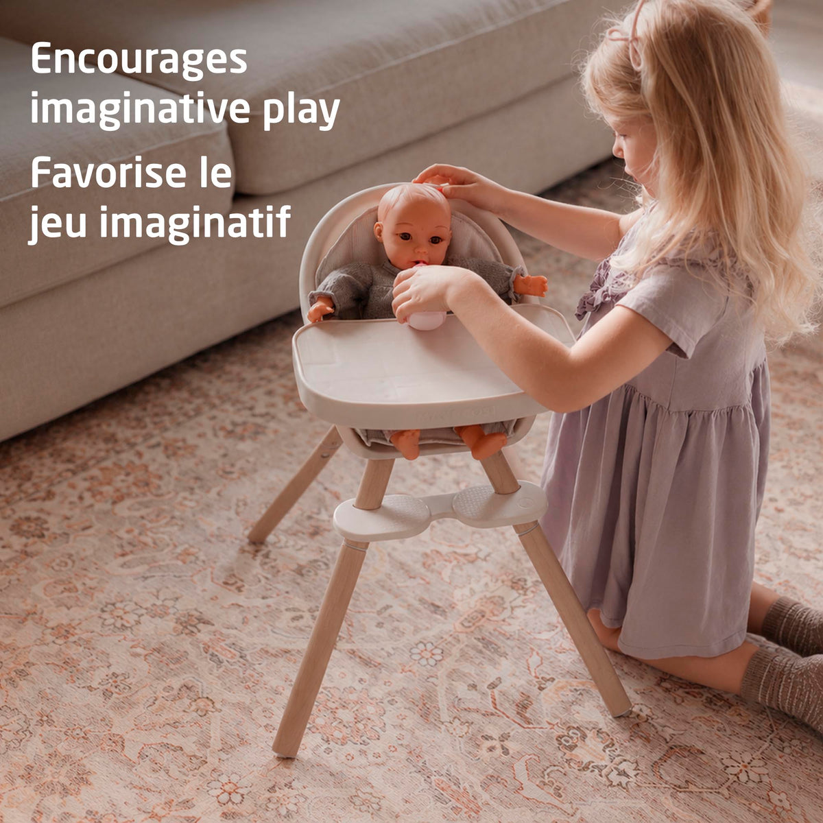 Young child tending lovingly to a doll in the Maxi-Cosi Moa high chair to encourage imaginative pretend play.